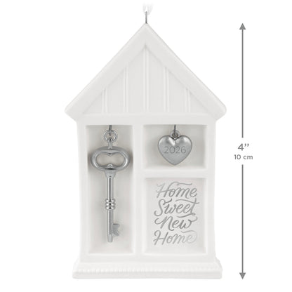 Home Sweet New Home 2026, porcelain and metal — 2026 Hallmark Keepsake Christmas Ornament, featuring a silver key and heart charm, flat lay.