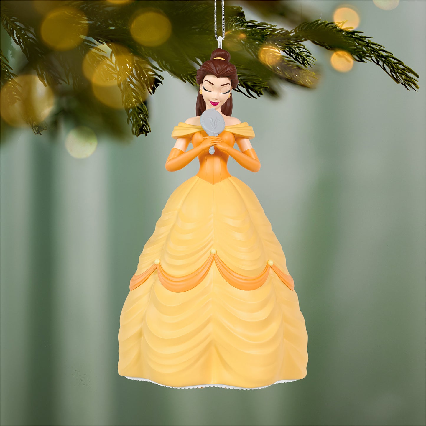 Disney Beauty and the Beast 35th Anniversary Belle With the Enchanted Mirror — 2026 Hallmark Keepsake Christmas Ornament hanging on a tree branch with blurred lights.
