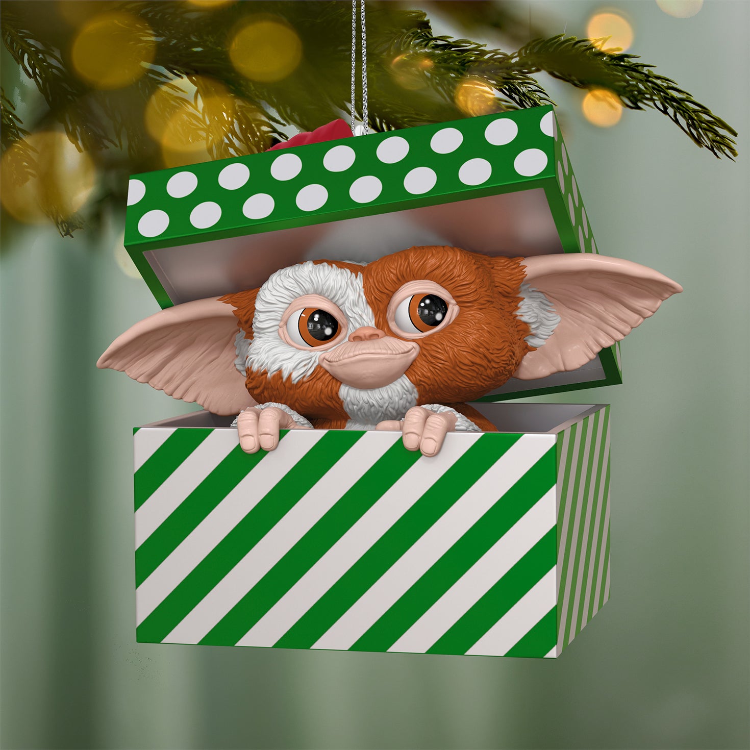 Gremlins Gizmo — 2026 Hallmark Keepsake Christmas Ornament peeking from a green and white striped gift box.