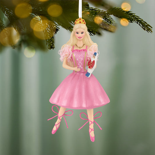 Barbie™ in the Nutcracker 25th Anniversary, porcelain and fabric ornament, featuring Barbie in a pink dress holding a toy, hanging on a tree.