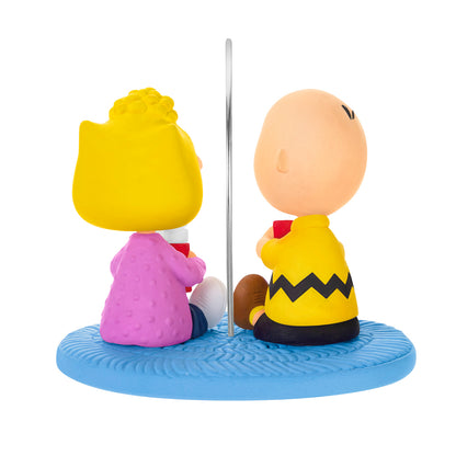 The Peanuts Gang More Marshmallows, Please! — 2026 Hallmark Keepsake Christmas Ornament featuring Charlie Brown and Sally sitting on a blue rug with hot chocolate.