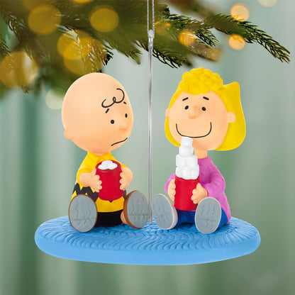 The Peanuts Gang More Marshmallows, Please! — 2026 Hallmark Keepsake Christmas Ornament features Charlie Brown and Sally sipping cocoa on a blue rug.