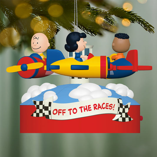 The Peanuts® Gang Off to the Races! Musical With Motion — 2026 Hallmark Keepsake Christmas Ornament featuring Charlie Brown, Lucy, and Franklin flying in colourful airplanes against a festive backdrop.