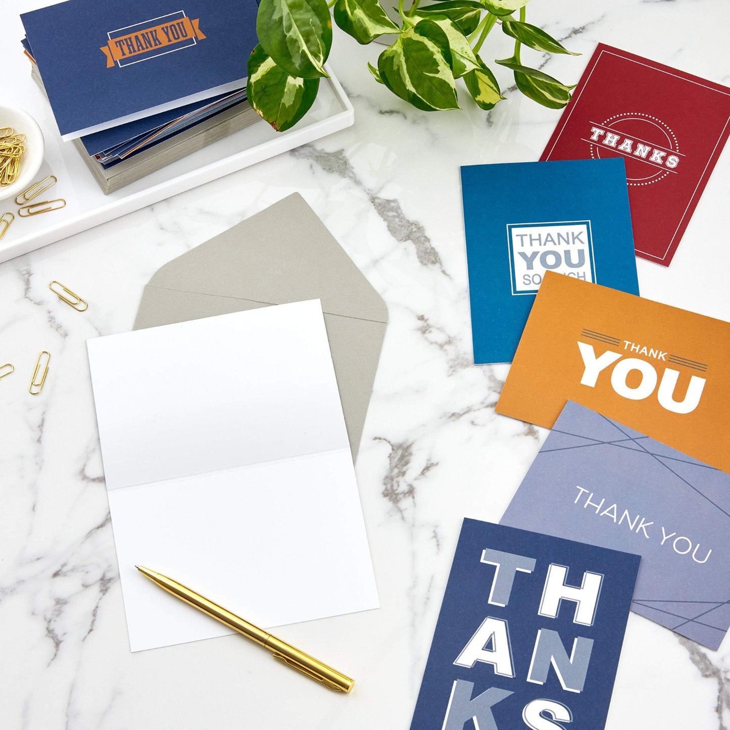Hallmark Thank You Cards Assortment, Bold Type featuring six colourful designs on a marble surface with a gold pen and envelopes.