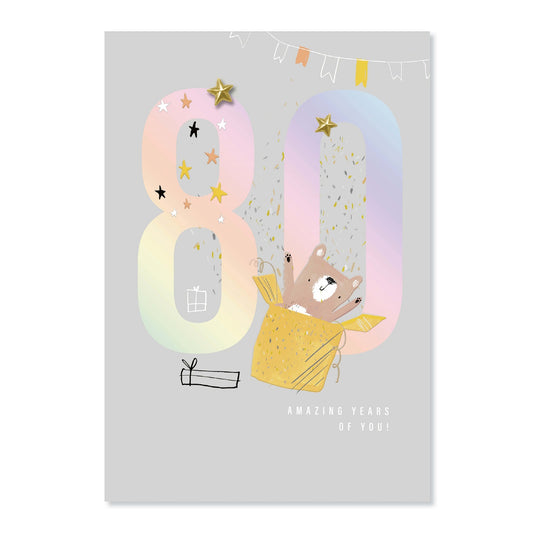 Connections from Hallmark 80th Birthday Card - 80 AMAZING YEARS OF YOU! features a cute bear in a gift box with colourful foil stars.