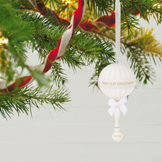 Baby's First Christmas (2023) Porcelain Rattle — Hallmark Keepsake Christmas Ornament hanging on a Christmas tree with gold accents and white bow.
