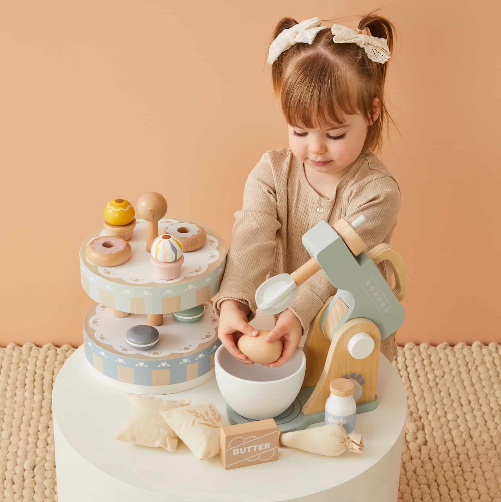 Wooden Cake Stand Set featuring a child playing with colourful wooden donuts and a mixer in a light, inviting setting.