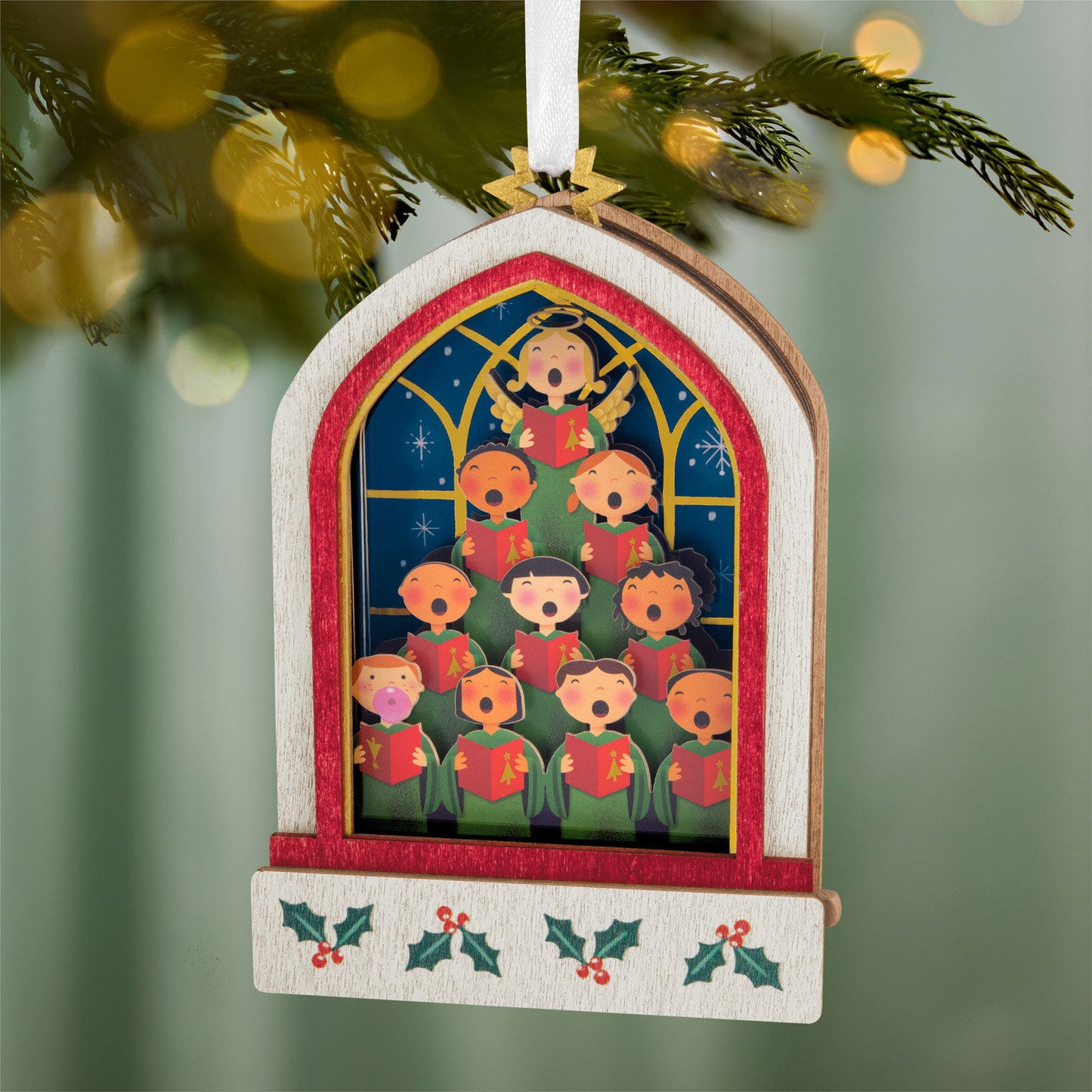 Lifting Their Voices Musical, Papercraft — 2026 Hallmark Keepsake Christmas Ornament with a choir of children in a church window design, hanging on a tree.