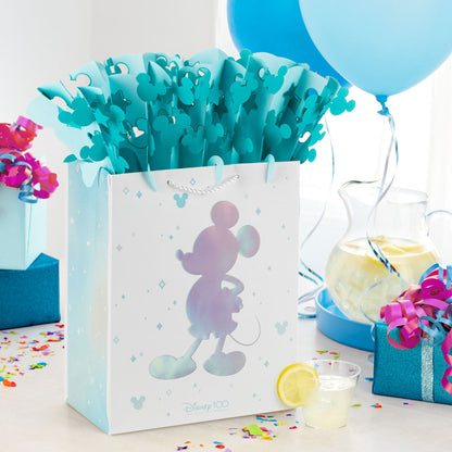 Disney 100 Years of Wonder large gift bag with WonderFill topper, featuring blue Mickey Mouse silhouette and paper, festive setting.