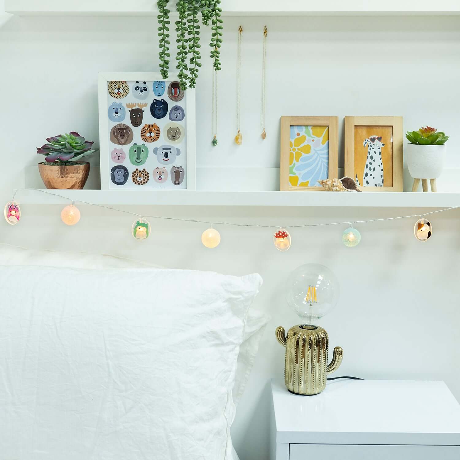 Squishmallows 2D string lights in a lifestyle scene featuring colourful lights over a shelf with framed art and a cactus lamp.