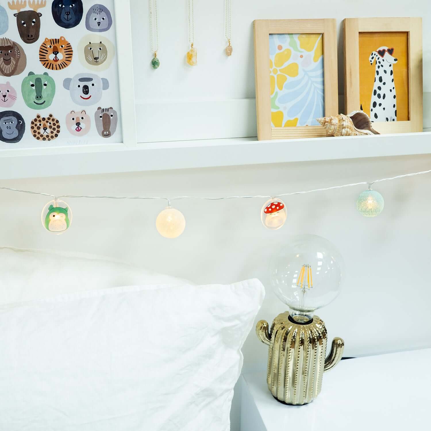 Squishmallows 2D String Lights featuring cute animal designs on a warm string, displayed above a white cushion in a contemporary bedroom setting.