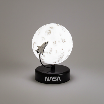 A NASA-themed space-themed night light featuring a glowing moon globe with a small metallic space shuttle accent, mounted on a black circular base printed with the NASA logo, set against a neutral gray background.
