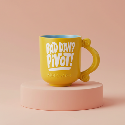 Firends tv show Yellow mug with 'Bad Day? Pivot!' text on a pink platform against a beige background