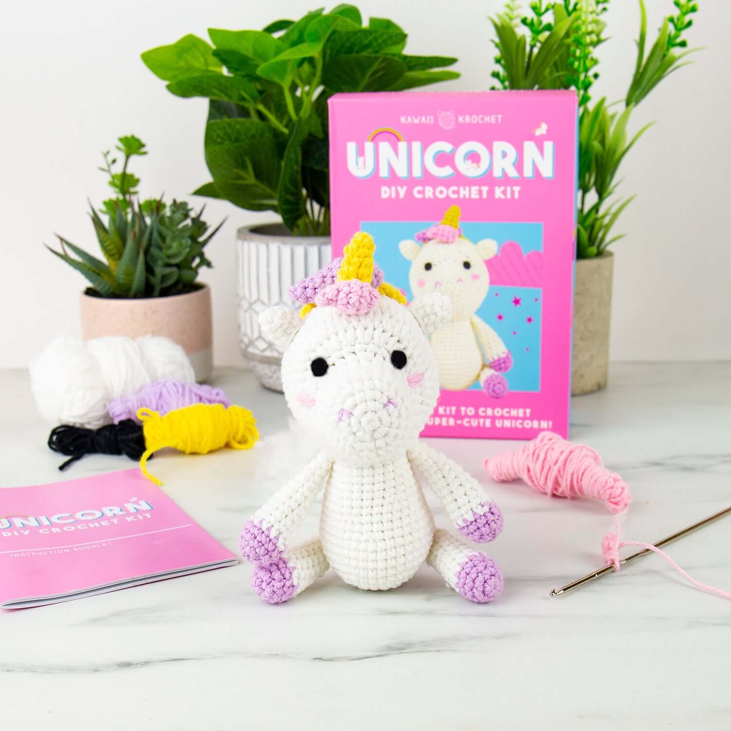 Unicorn DIY crochet kit displayed with a completed crochet unicorn, colourful yarn, and instruction booklet in a bright setting.
