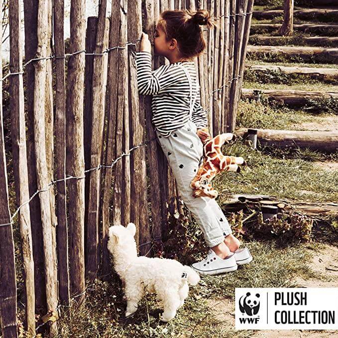 WWF Alpaca White - 31 cm - 12" plush toy beside a child exploring a fence, soft and cuddly design in outdoor setting.