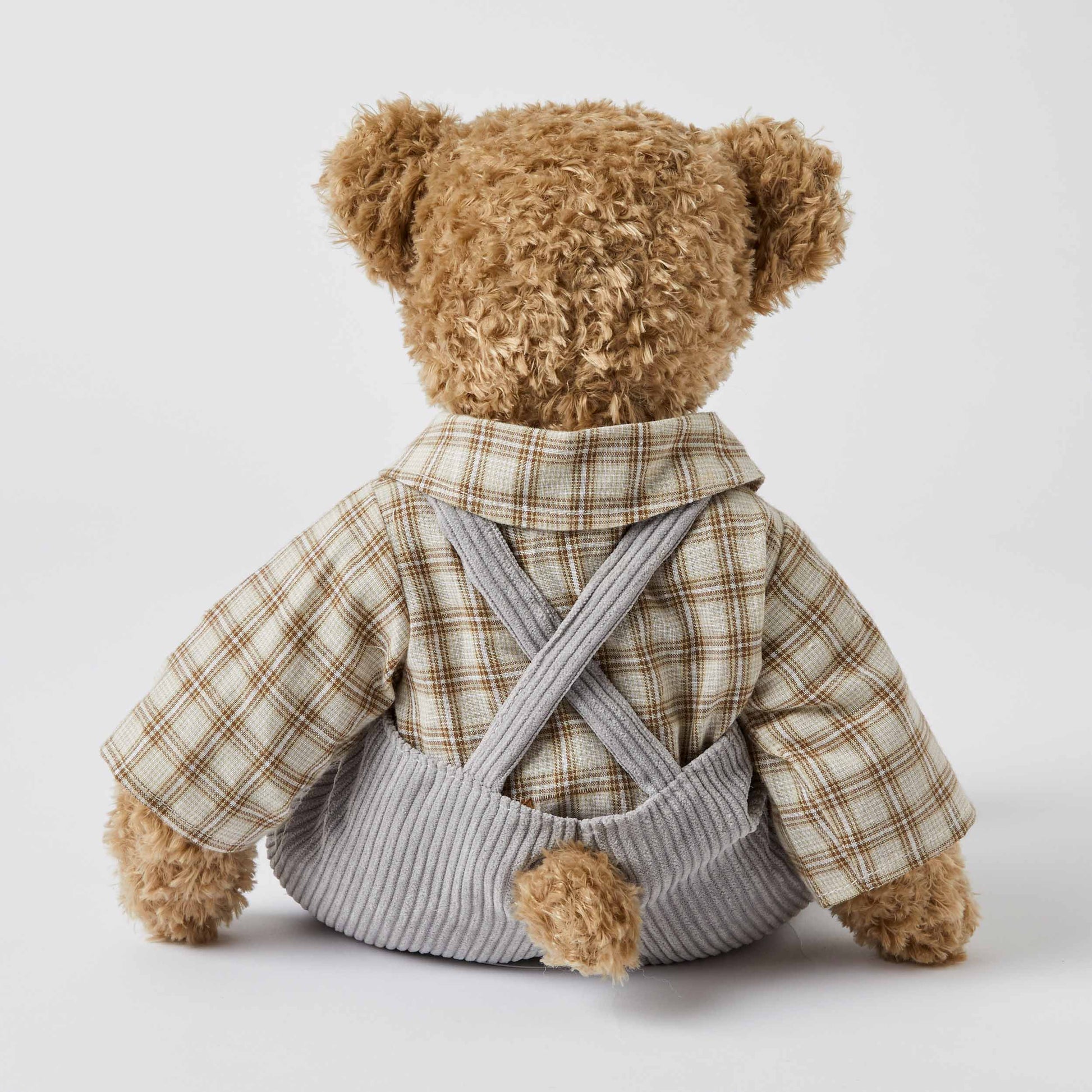 Chester the Notting Hill Bear in grey corduroy overalls and plaid shirt, back view showcasing fur texture and details.