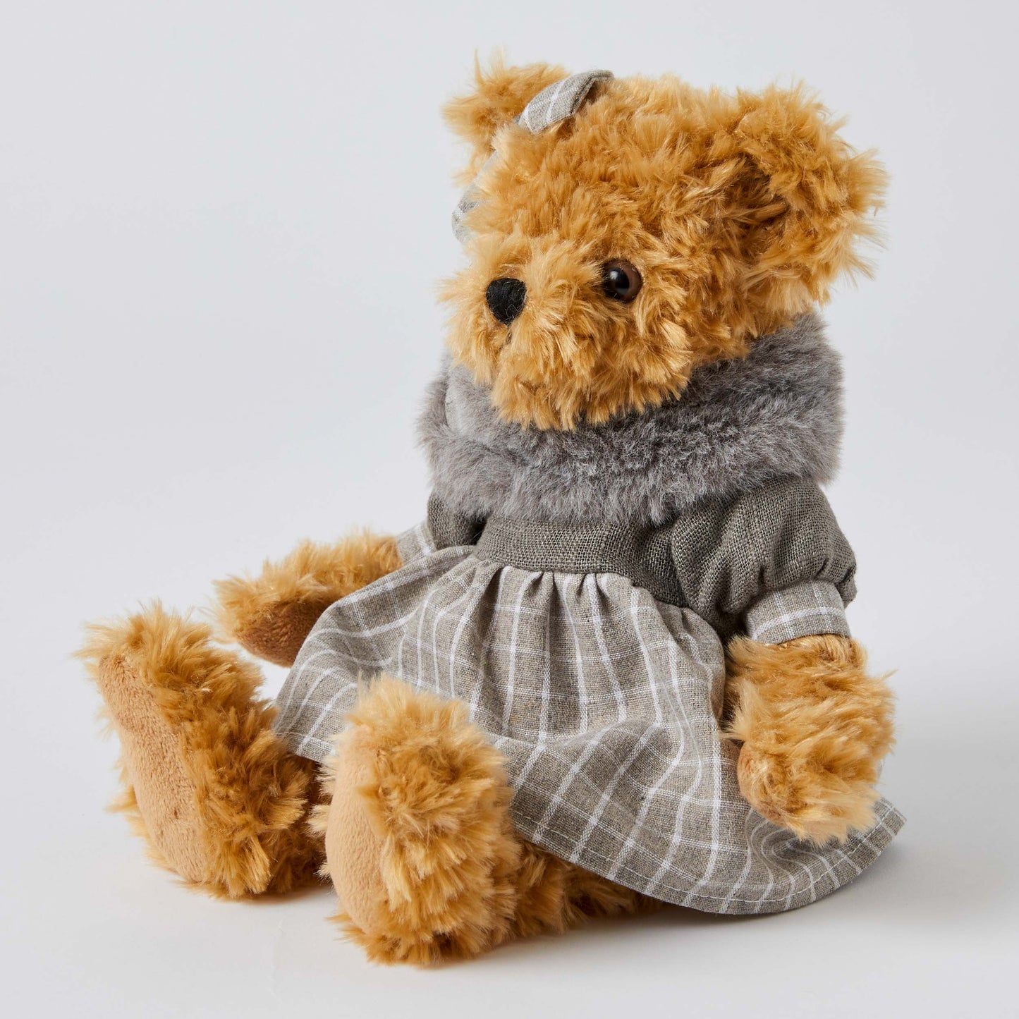 Beatrice the Notting Hill Bear in a plaid dress and grey faux fur scarf, sitting pose with a bow in her hair.