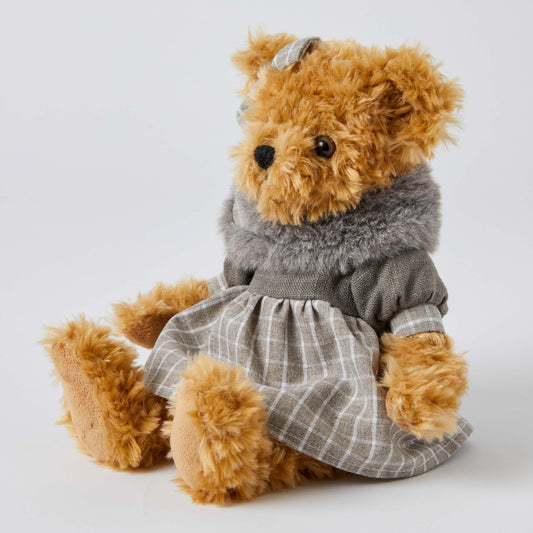 Beatrice the Notting Hill Bear in a plaid dress and grey faux fur scarf, sitting pose with a bow in her hair.