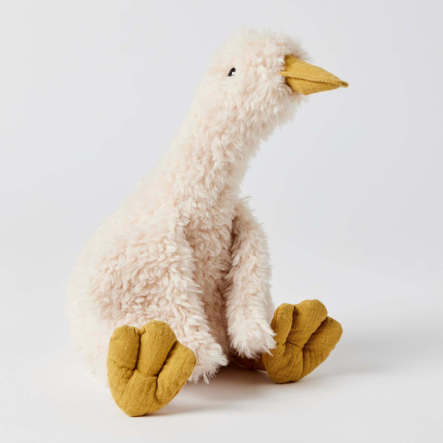 Wiggles the Duck plush toy in cream with yellow feet, sitting pose highlighting its soft texture and playful design.
