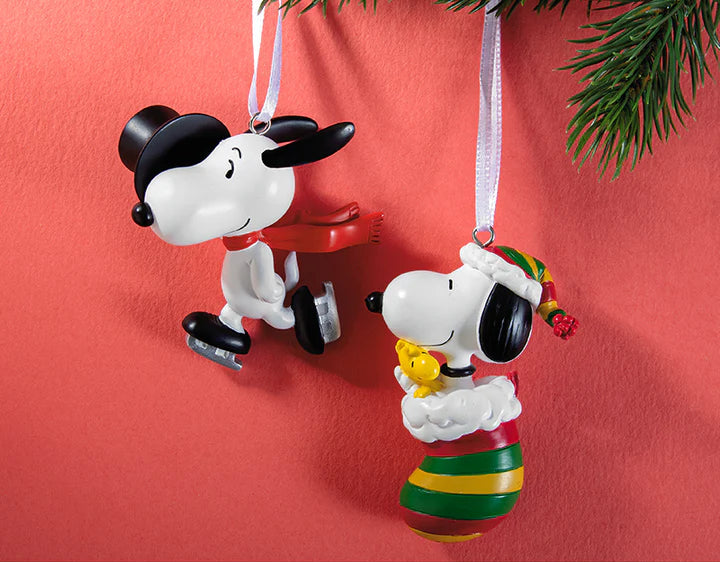 Two Christmas ornaments featuring black and white dog characters on a red background with 'Peanuts' branding.