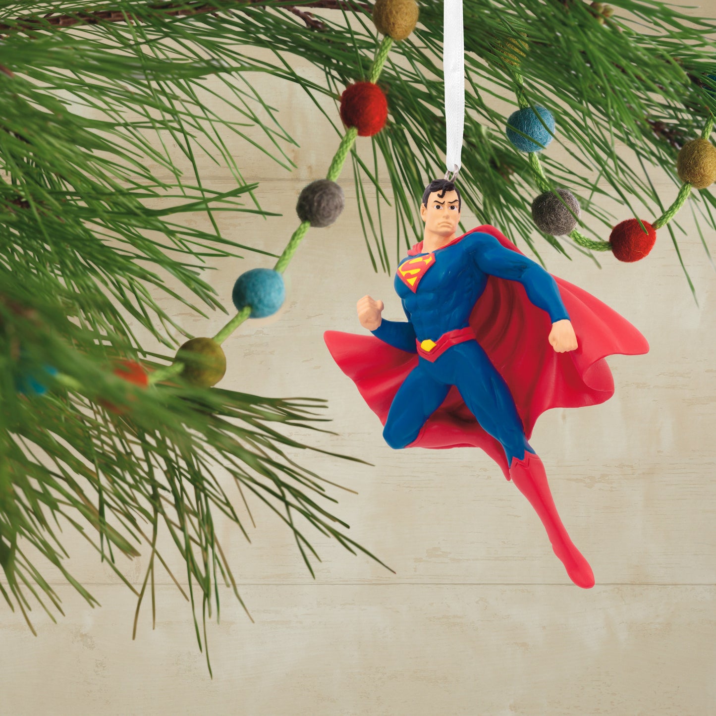 Resin Figural Superman ornament hanging from a pine tree branch, bright colours and detailed design enhance holiday decorations.