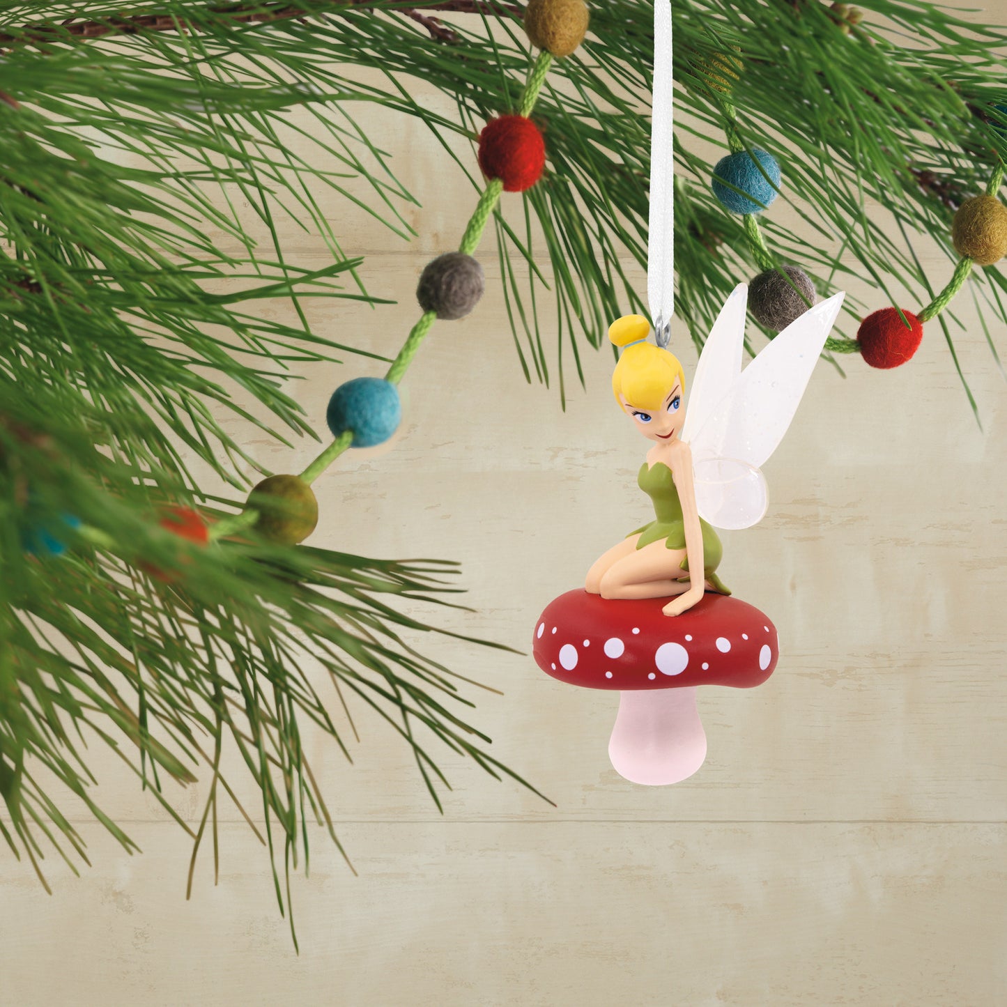 Hallmark Christmas Ornament - Disney Tinker Bell on Mushroom decorated with a red-and-white mushroom, hanging from a pine branch