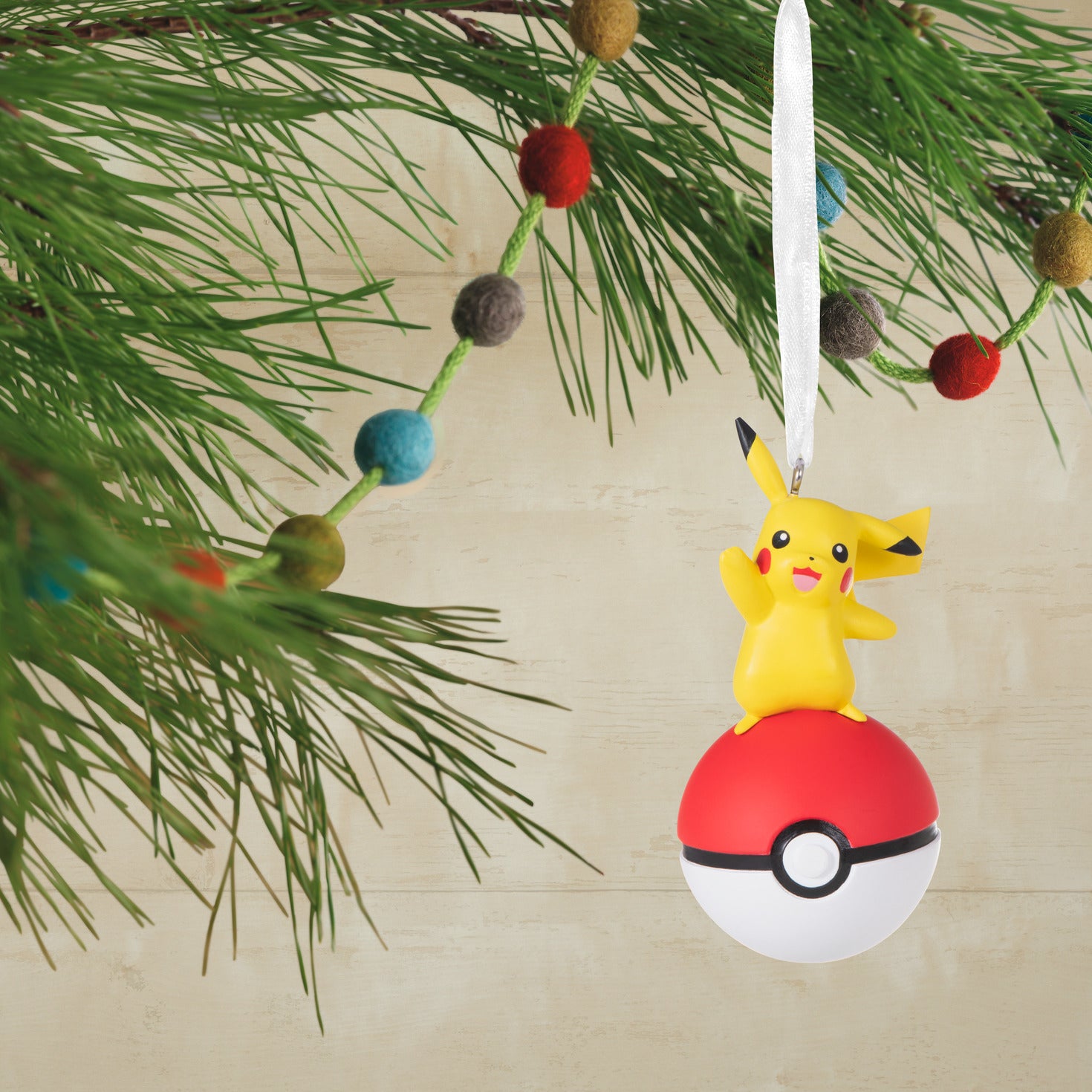 Hallmark Christmas Ornament - Pokémon Pikachu on Poké Ball hanging from a festive pine tree branch with colourful baubles.