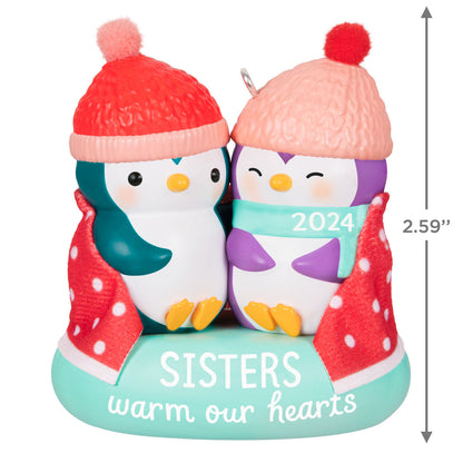 Sisters Warm Our Hearts — Hallmark Keepsake Christmas Ornament featuring two penguins in hats under a polka dot blanket, 2024 date.