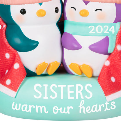 Sisters Warm Our Hearts — Hallmark Keepsake Christmas Ornament, ceramic penguins in polka dot blanket, close-up detail of 2024 inscription.