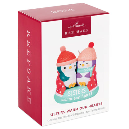 Sisters Warm Our Hearts — Hallmark Keepsake Christmas Ornament gift box featuring penguins in hats and polka dot blanket, 2024 design.
