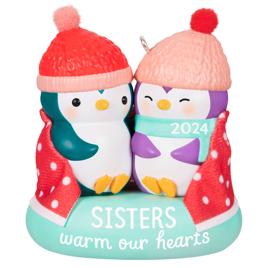 Sisters warm our hearts — Hallmark Keepsake Christmas ornament featuring two penguins in hats with a polka dot blanket.