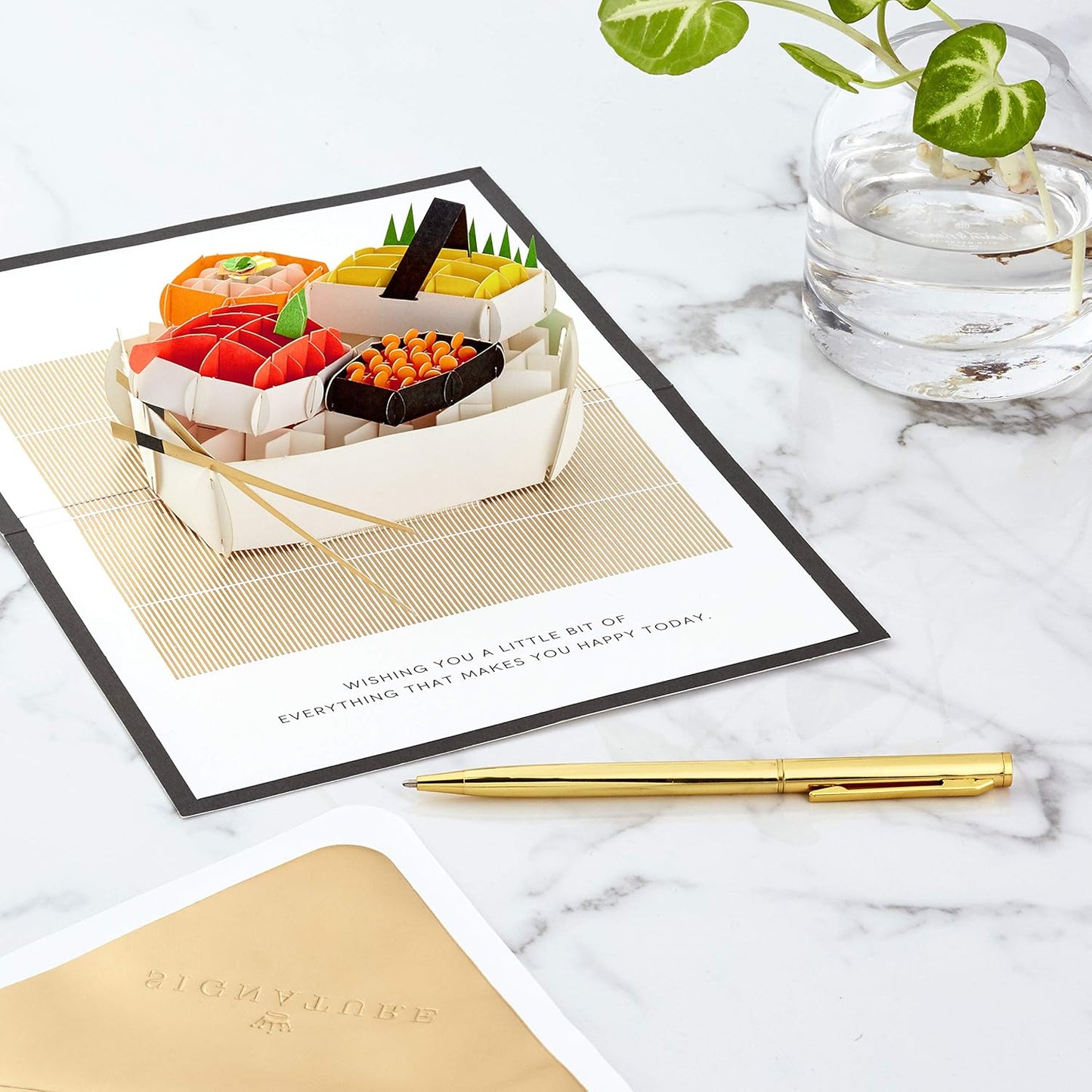 Hallmark Signature Paper Wonder Pop Up Birthday Card (Sushi, Everything That Makes You Happy) featuring intricate pop-up sushi design on a marble surface with a gold pen.