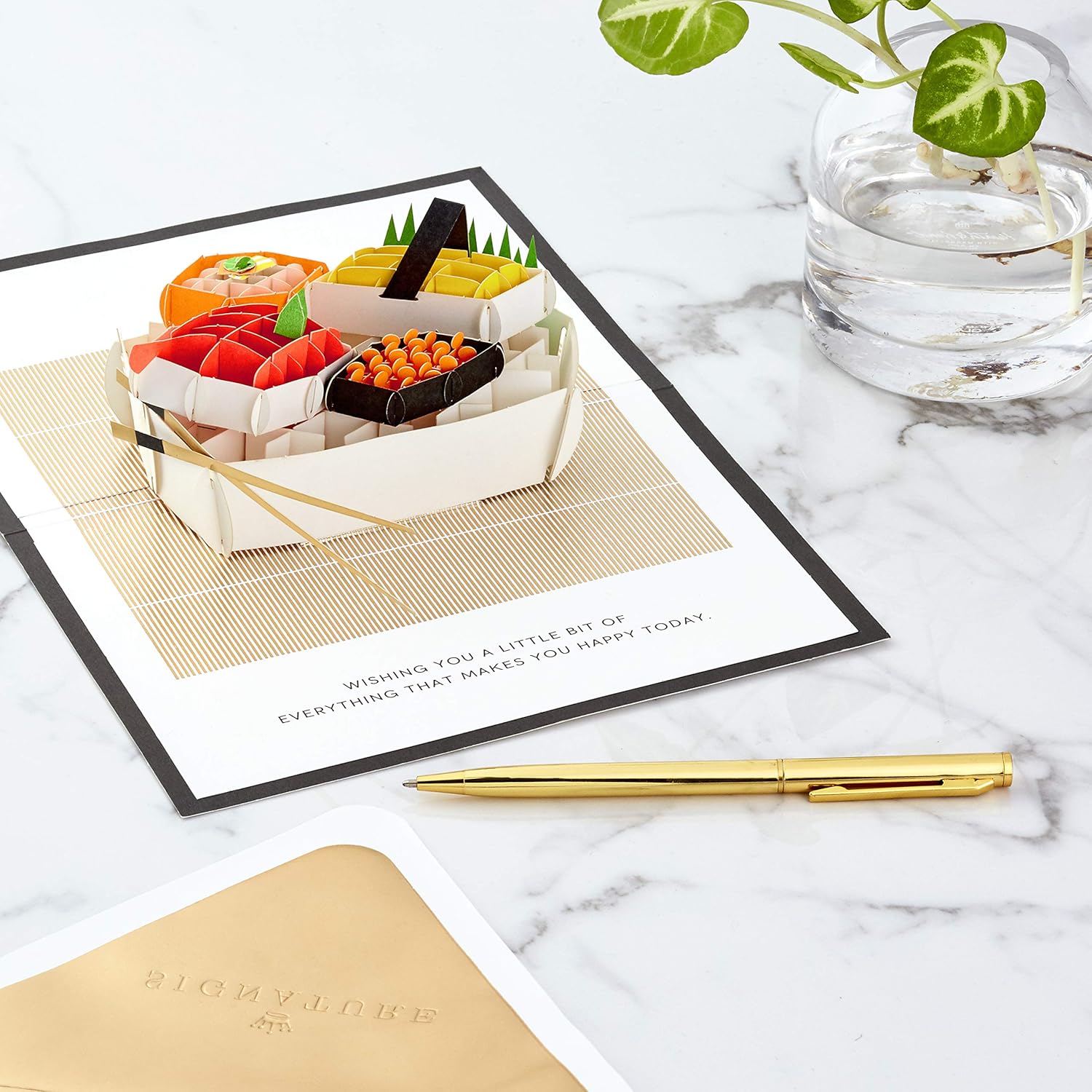 Hallmark Signature Paper Wonder Pop Up Birthday Card (Sushi, Everything That Makes You Happy) featuring intricate pop-up sushi design on a marble surface with a gold pen.