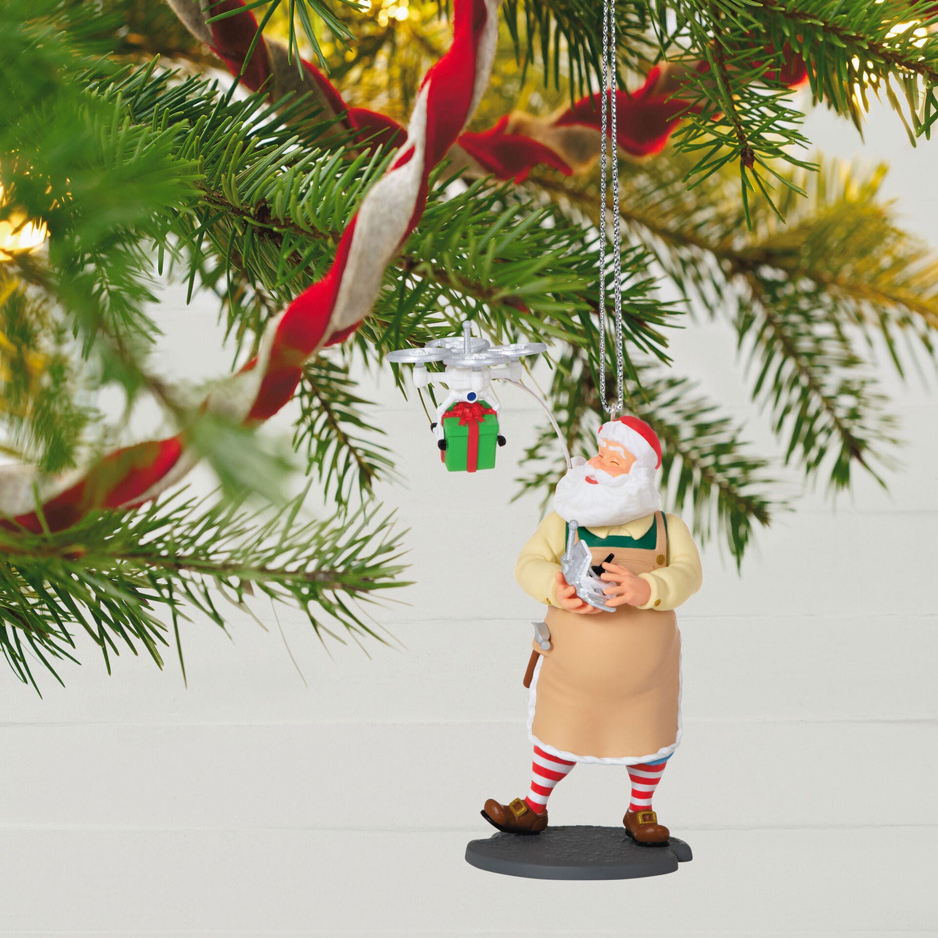 Toymaker Santa — Hallmark Keepsake Christmas Ornament, jolly Santa with a drone delivering a gift, hanging on a Christmas tree branch.