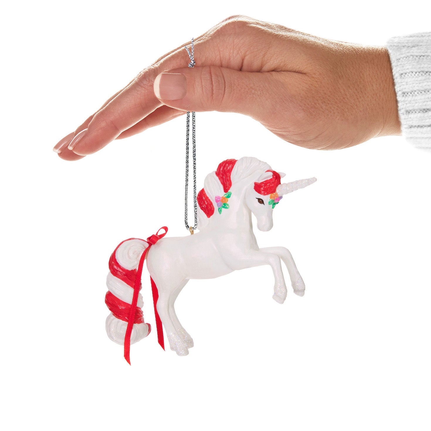Sweet Unicorn — Hallmark Keepsake Christmas Ornament held by a hand, featuring a candy cane-striped mane and tail with floral accents.