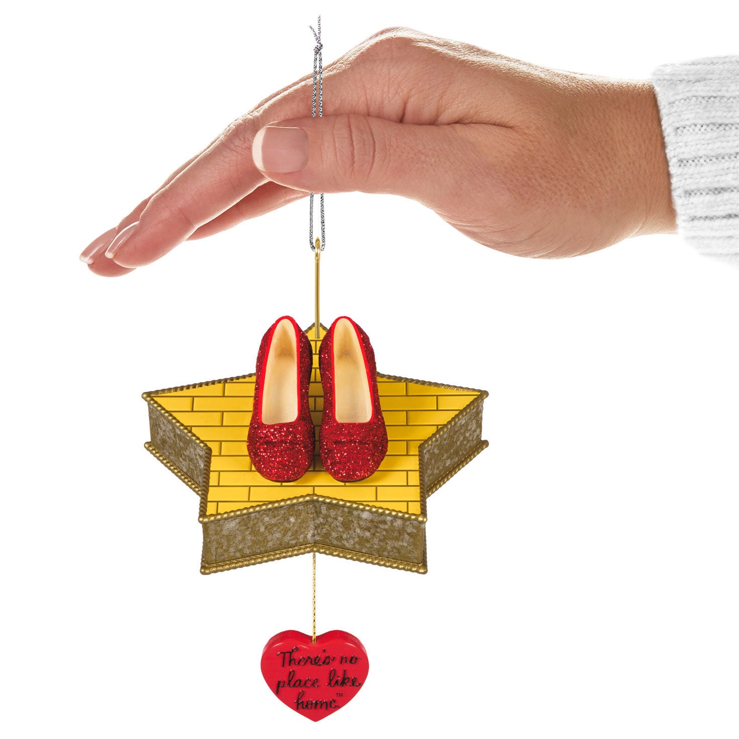 The Wizard of Oz™ There's No Place Like Home™ — Hallmark Keepsake Christmas Ornament featuring Ruby Slippers on a star platform, held by hand.