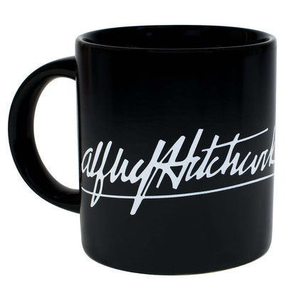 Unemployed Philosophers Guild - Alfred Hitchcock Mug in black ceramic with signature design, angled view showing handle.