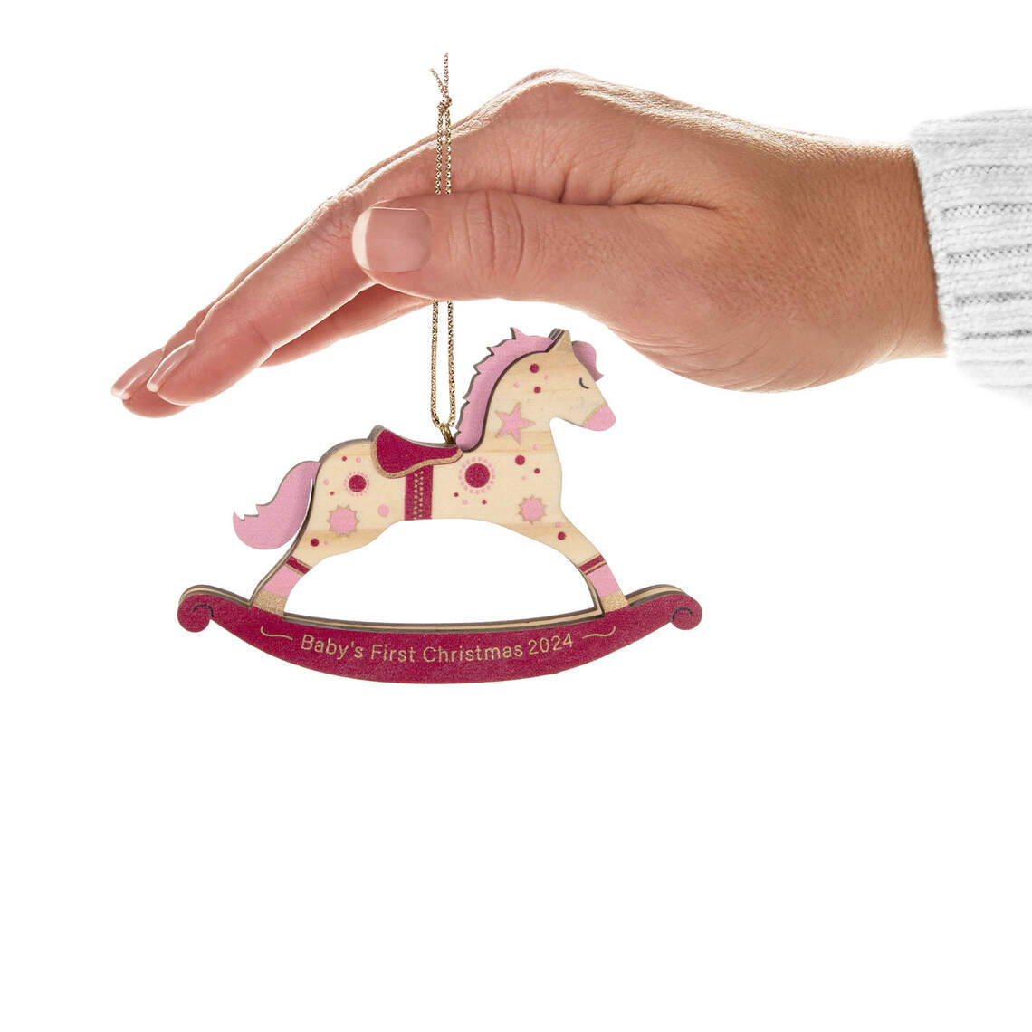Baby girl's first Christmas rocking horse wood — Hallmark Keepsake Christmas ornament held by a hand with pink and gold details.