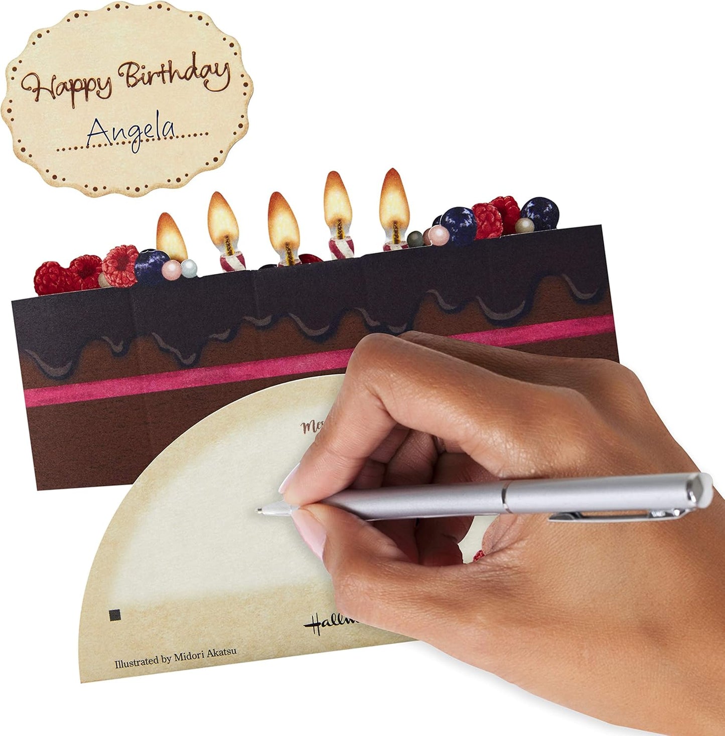 Hallmark Pop Up Birthday Card (Chocolate Cake) featuring a hand writing a personal message on a smooth surface with a pop-up cake design.