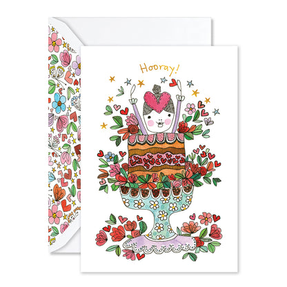 Hallmark x Love, Meredith Birthday Greeting Card - Hooray! featuring a girl jumping out of a cake with floral details and gold foil accents.