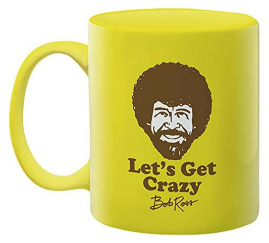 Bob Ross - Let's Get Crazy Ceramic Mug in bright yellow with a smiling face design and black text, angled view showcasing handle.