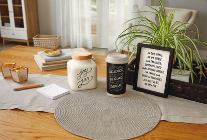 Ceramic Joy Jar and Notepad Set displayed on a wooden table with decorative elements, including a plant and inspirational frame.