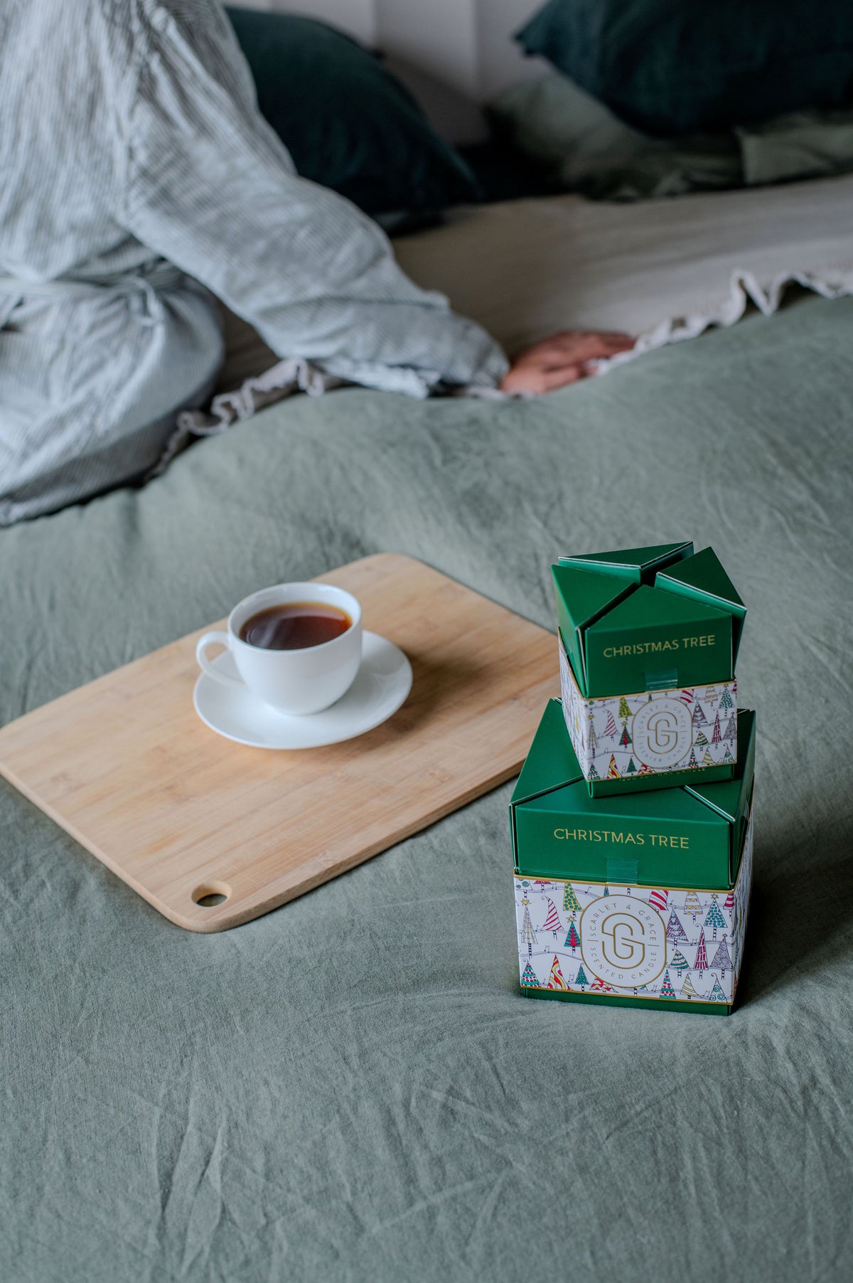 Christmas Tree Candle - Limited Edition (380g) displayed on a wooden board with tea cup, featuring green and festive packaging.