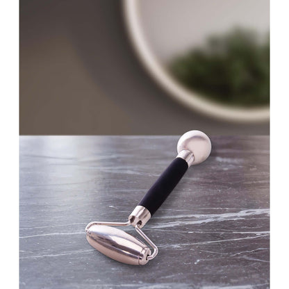 5 Cooling Facial Roller with stainless steel and black silicone handle on marbled surface, angled view showcasing design.