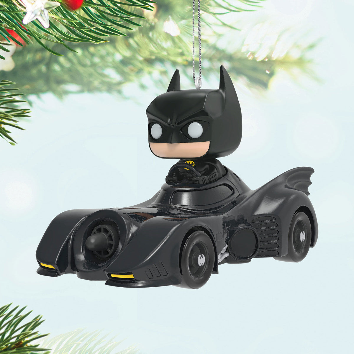 DC™ 1989 Batman™ in His Batmobile™ Funko POP!® ornament, black plastic design, hanging from a Christmas tree with festive greenery.