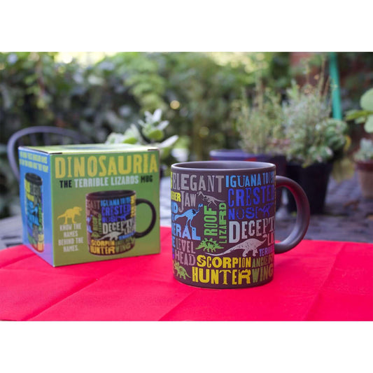 Unemployed Philosophers Guild - Dinosaur Mug featuring colourful dinosaur-themed designs with packaging on a red table.