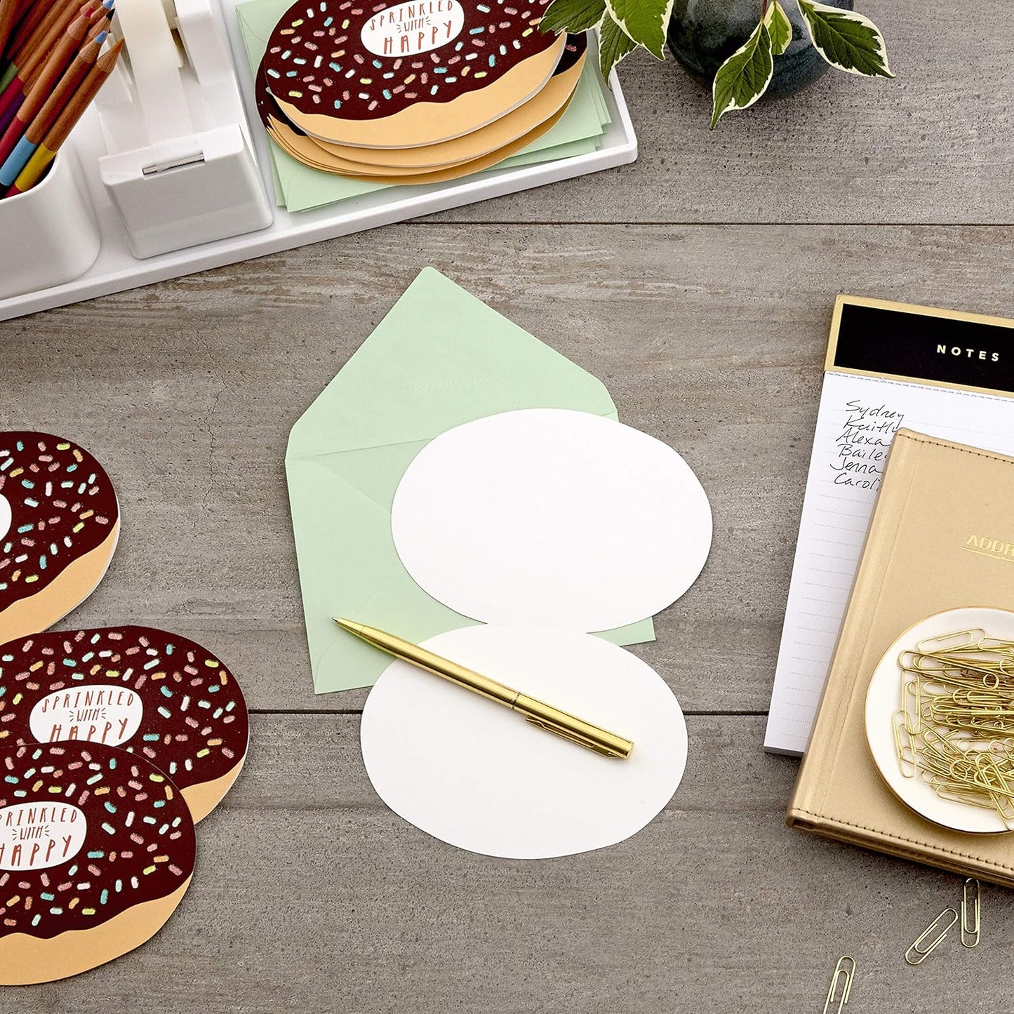 Hallmark Pack of Blank Cards, Donuts (15 Cards with Envelopes) displayed flat with green envelope and gold pen on a wooden desk.