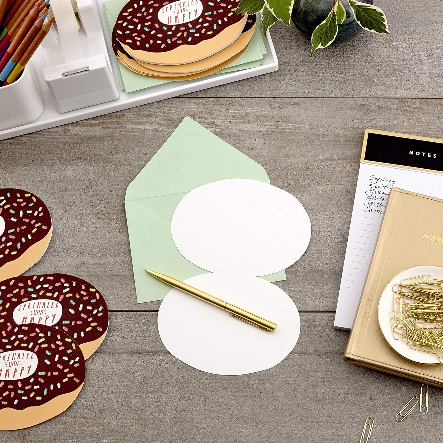 Hallmark Pack of Blank Cards, Donuts (15 Cards with Envelopes) displayed flat with green envelope and gold pen on a wooden desk.