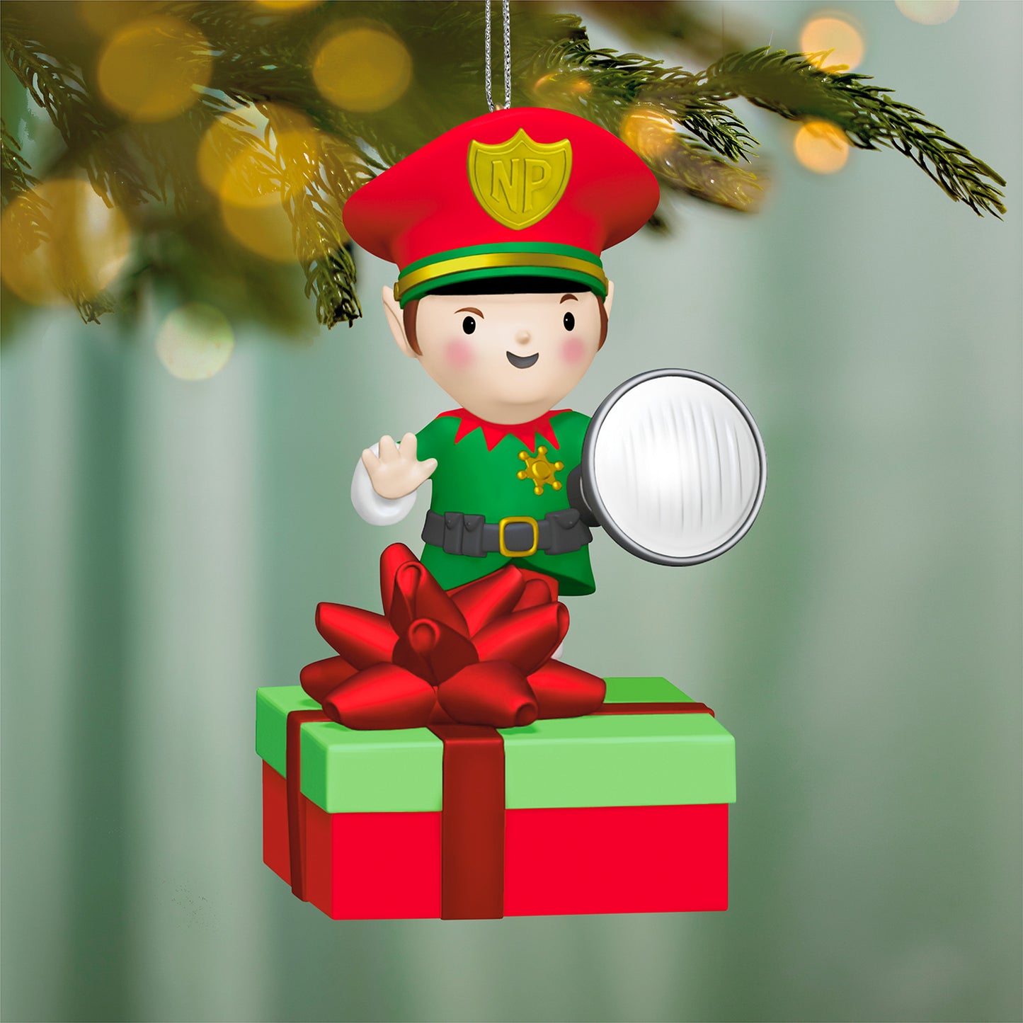 Elf Security Peekbuster With Motion-Activated Sound and Light — 2026 Hallmark Keepsake Christmas Ornament, festive ornament hanging from tree, featuring elf in green uniform with flashlight near wrapped gift.