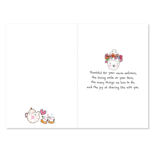 Card with cartoon teapot and cups on one side and floral design and text on the other, on a white background.